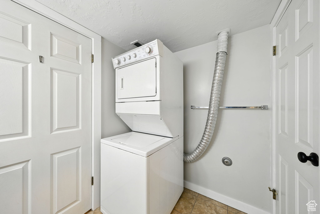 Washroom with estacked washer and dryer and baseboards