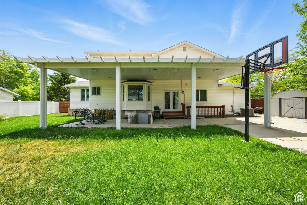 Rear view of property featuring french doors, a storage shed, and a patio area