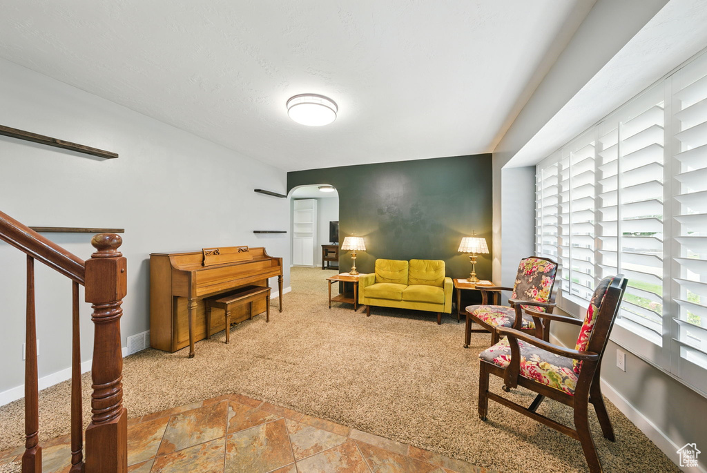Living area with arched walkways, stone finish floors, carpet floors, and stairs