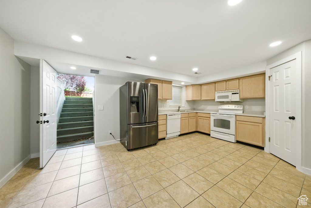 Kitchen featuring white appliances, light brown cabinets, light countertops, light tile patterned floors, and recessed lighting