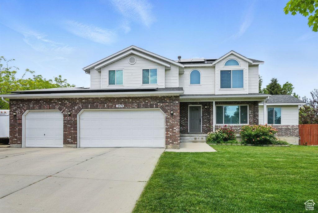 View of front facade featuring roof mounted solar panels, concrete driveway, brick siding, and an attached garage