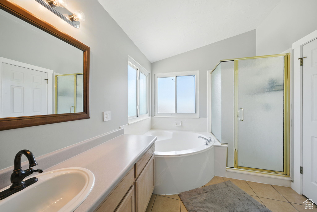 Bathroom featuring vaulted ceiling, a stall shower, tile patterned flooring, a garden tub, and vanity
