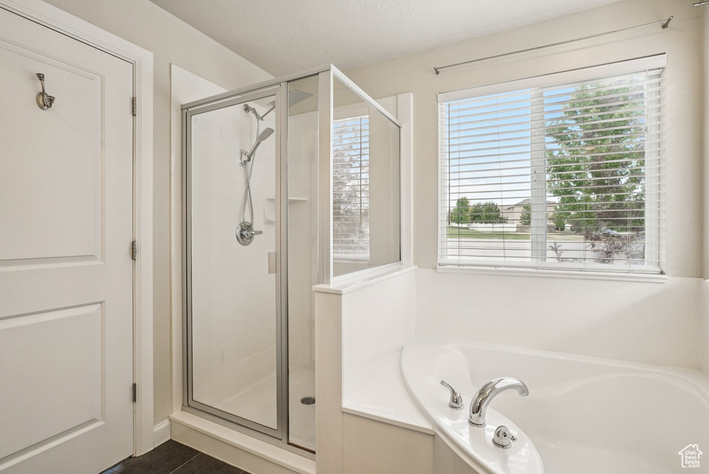 Bathroom featuring a stall shower, a bath, and plenty of natural light