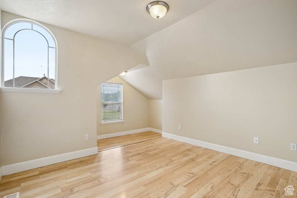 Additional living space featuring wood finished floors and vaulted ceiling