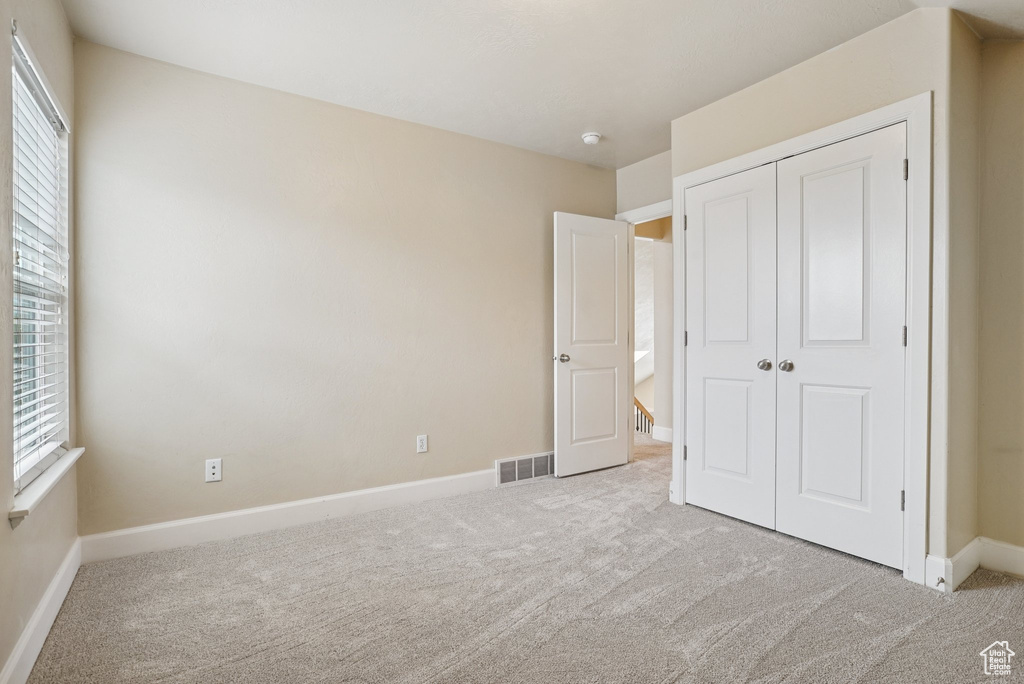 Unfurnished bedroom featuring carpet flooring and a closet