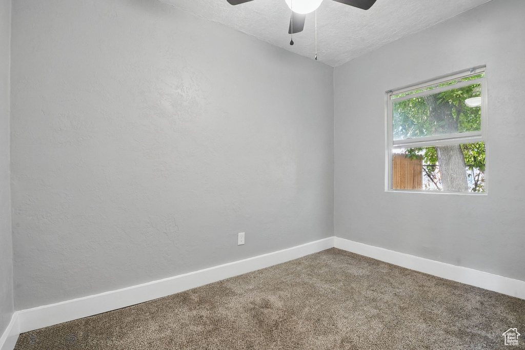 Carpeted spare room with a ceiling fan and a textured ceiling