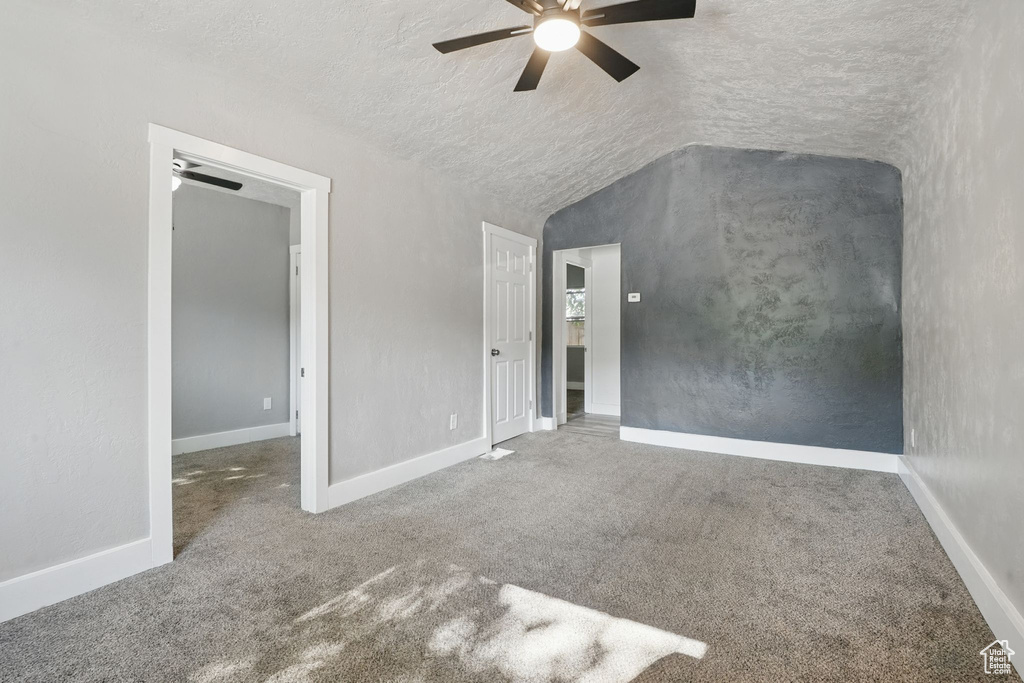 Unfurnished bedroom featuring carpet, lofted ceiling, a textured ceiling, and ceiling fan