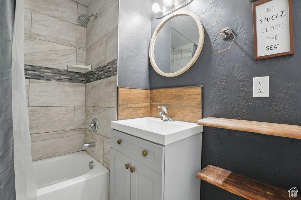 Bathroom with shower / bath combination with curtain, vanity, and a textured wall