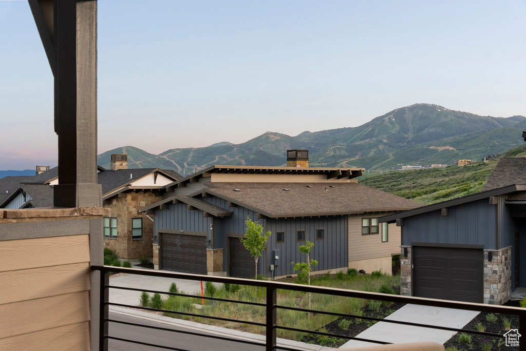 View of front of property with a balcony, a mountain view, a chimney, roof with shingles, and board and batten siding