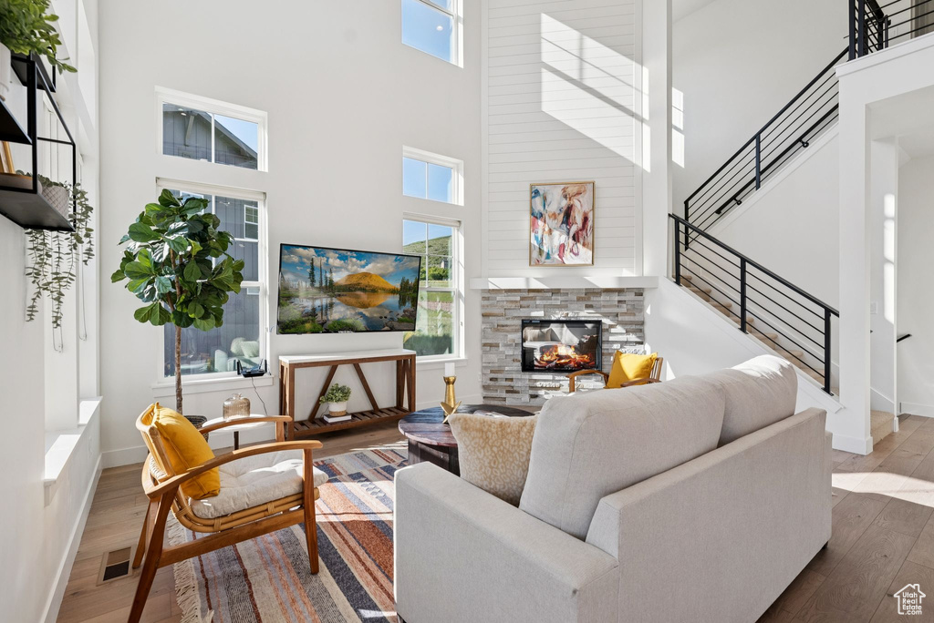 Living area with a high ceiling, wood finished floors, and a fireplace