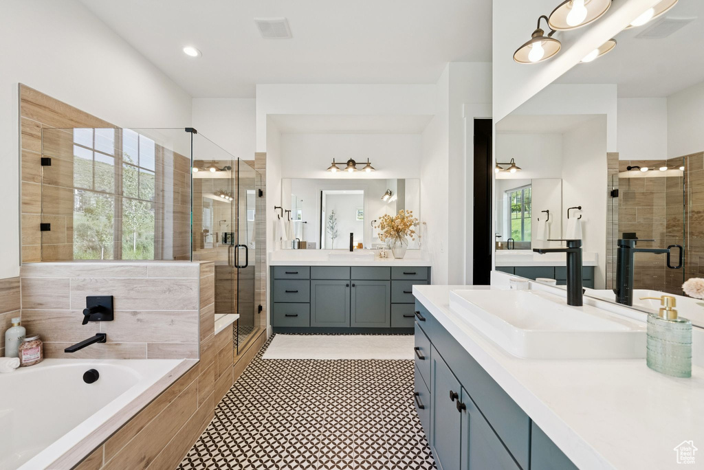Full bath with a stall shower, two vanities, a bath, and tile patterned floors