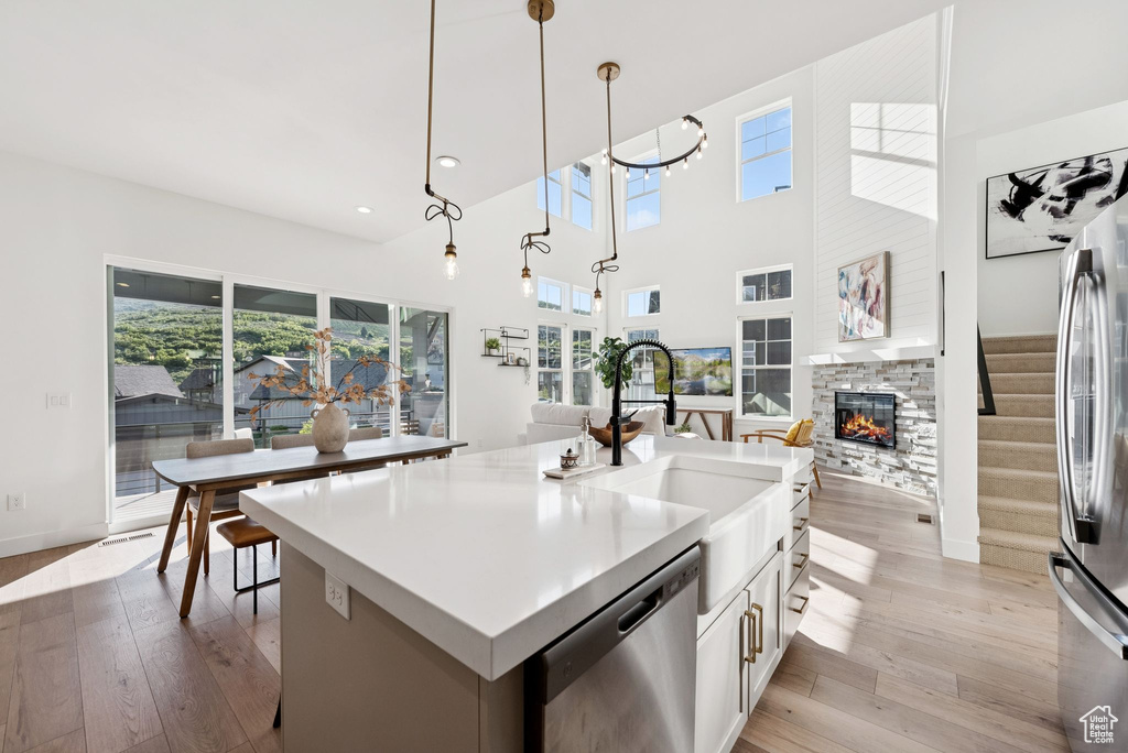 Kitchen featuring stainless steel dishwasher, healthy amount of natural light, a stone fireplace, light wood-type flooring, and recessed lighting