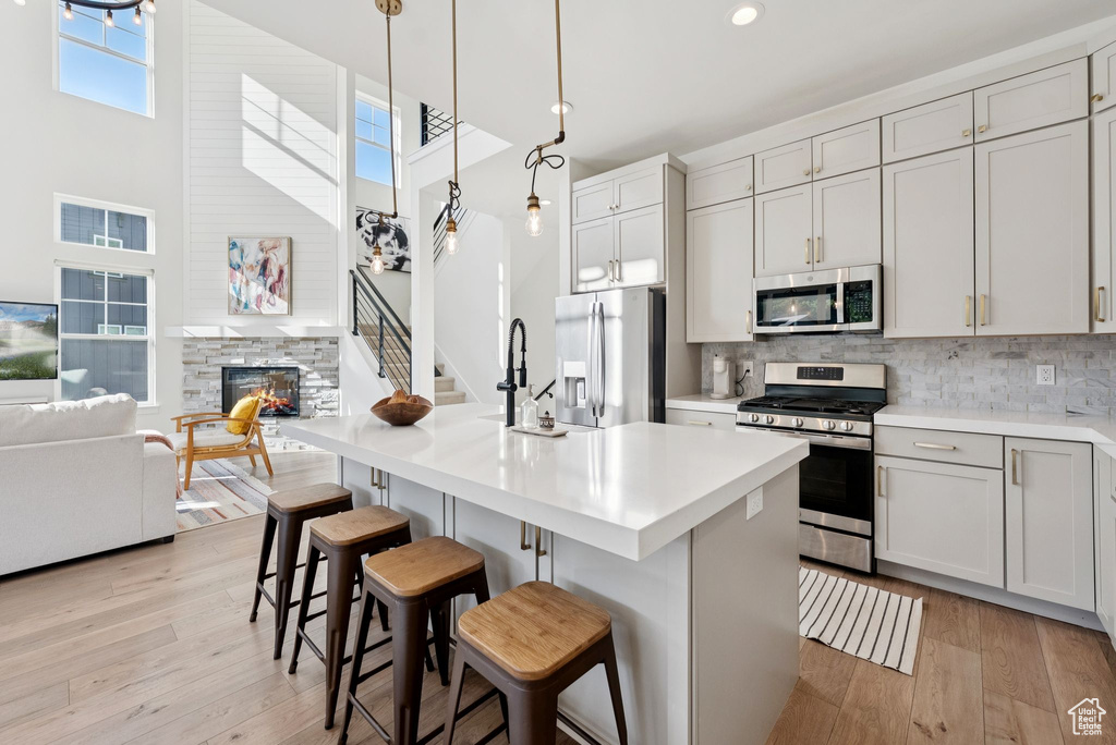 Kitchen with appliances with stainless steel finishes, a towering ceiling, light wood-style flooring, light countertops, and recessed lighting