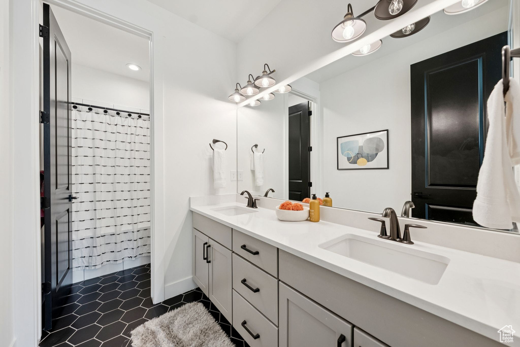 Full bathroom with double vanity, tile patterned flooring, and curtained shower