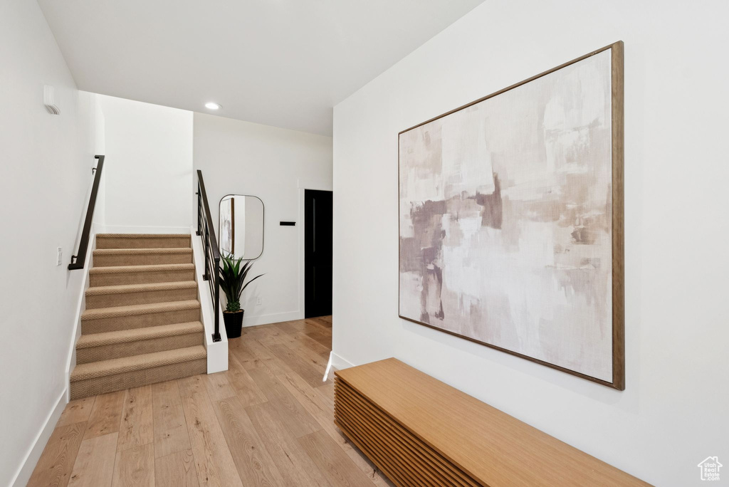 Corridor featuring light wood-style flooring, stairs, and recessed lighting