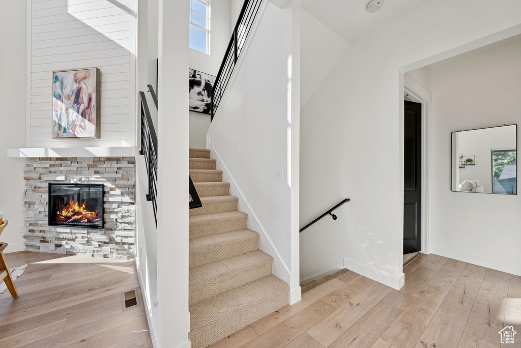Stairway featuring wood-type flooring and a stone fireplace