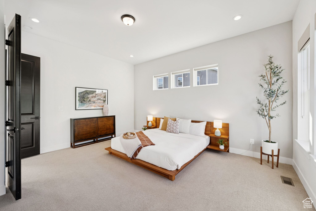 Bedroom with light carpet, multiple windows, and recessed lighting