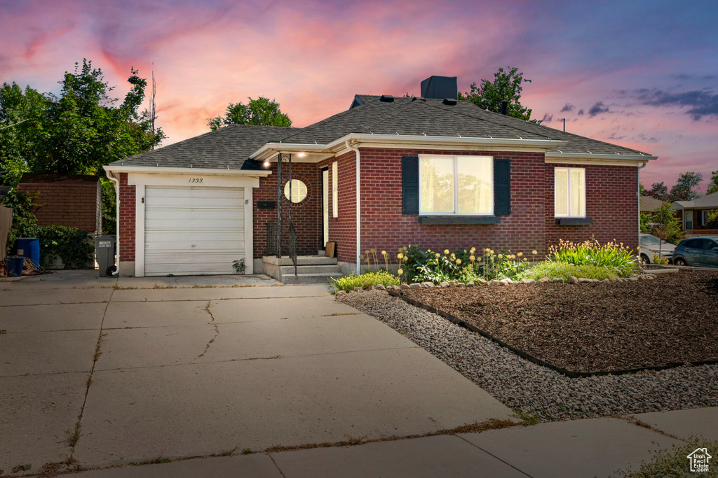 View of front of house featuring driveway, an attached garage, brick siding, and roof with shingles