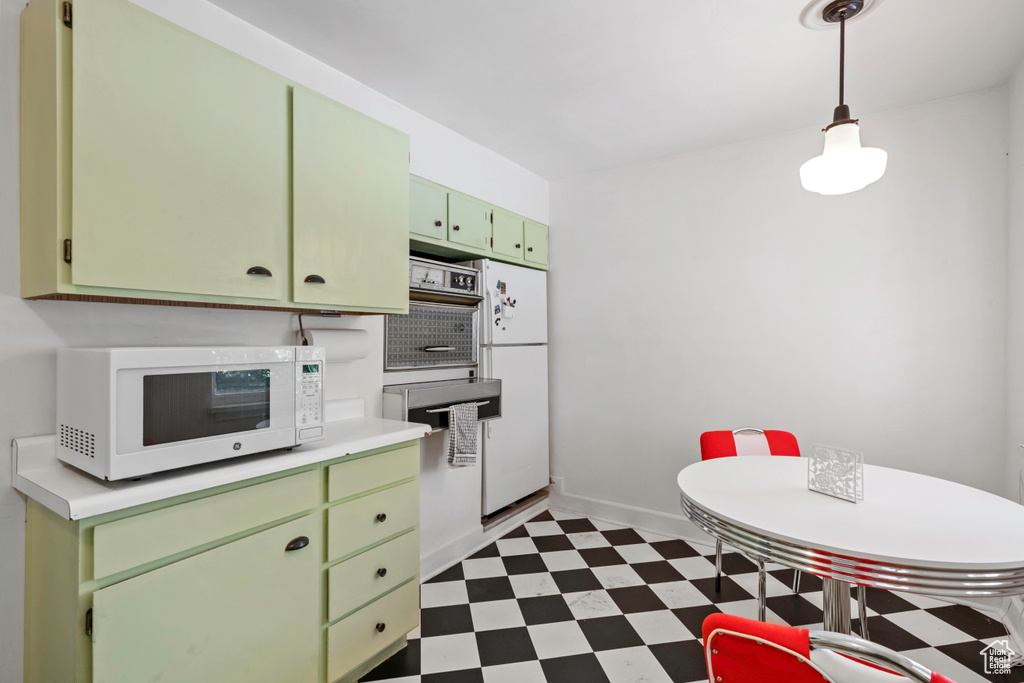 Kitchen with white appliances, green cabinets, dark floors, light countertops, and baseboards