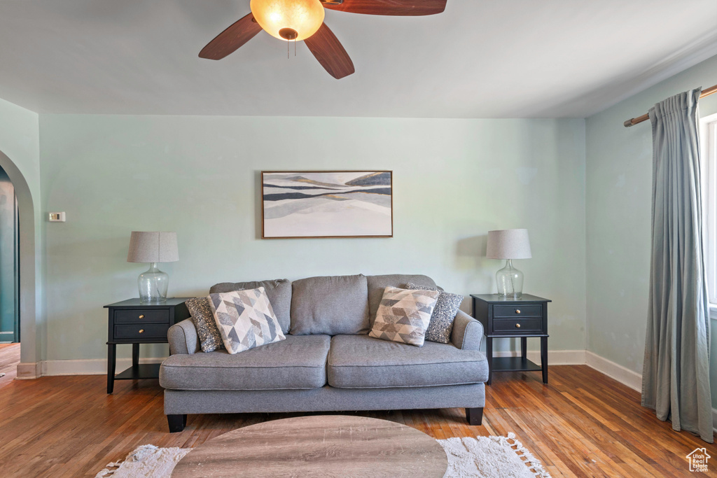 Living room featuring arched walkways, baseboards, wood finished floors, and a ceiling fan