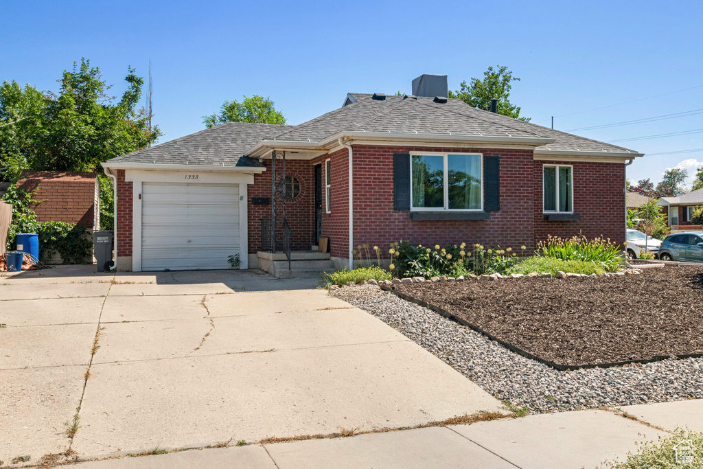 View of front of home with concrete driveway, a garage, brick siding, and a shingled roof