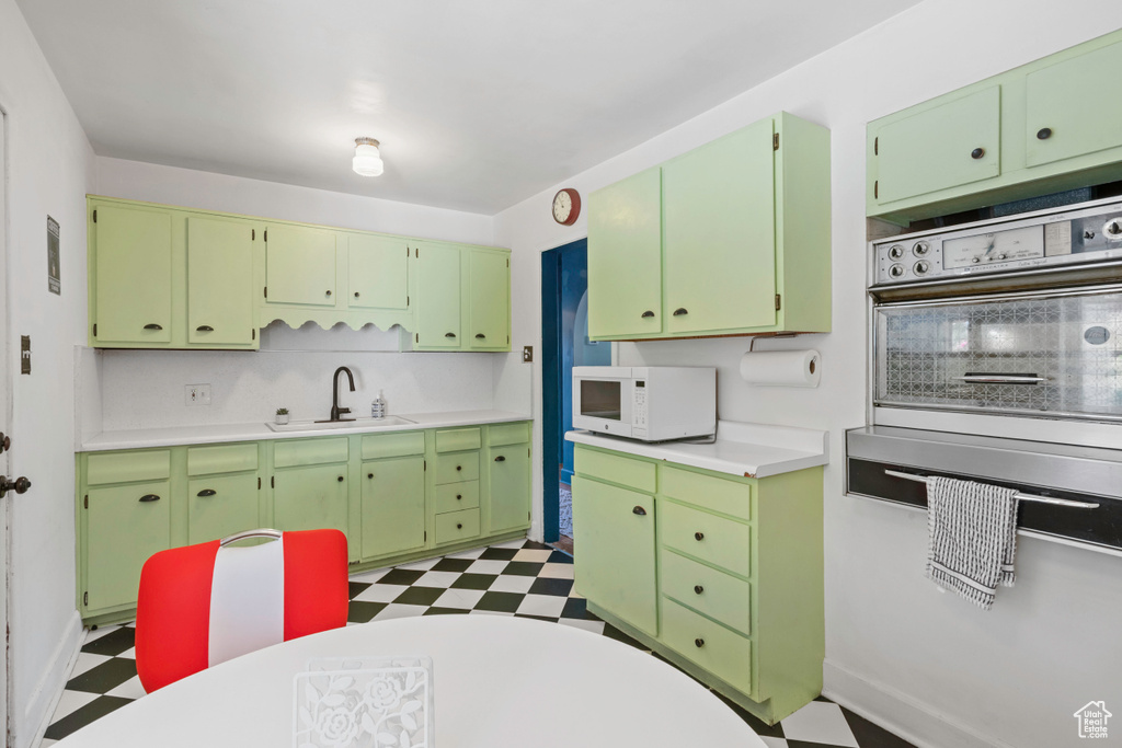 Kitchen featuring white appliances, a sink, dark flooring, and light countertops