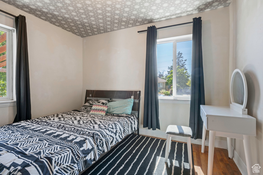Bedroom with wood finished floors, multiple windows, and baseboards