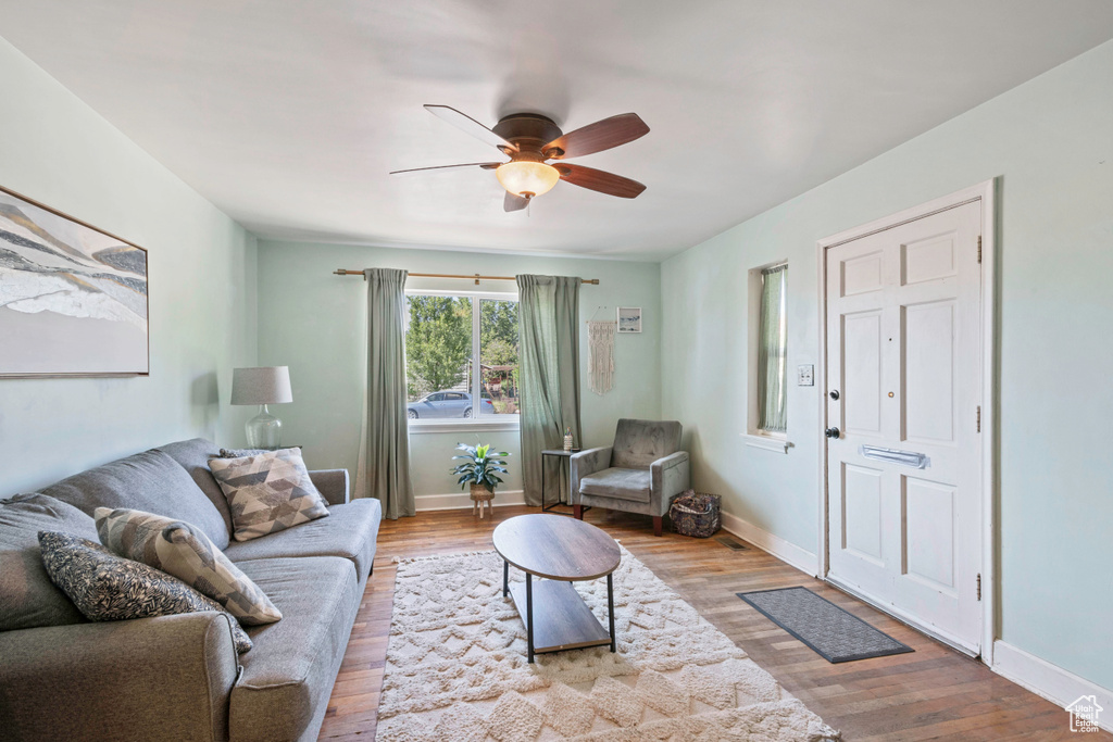 Living area featuring ceiling fan, wood finished floors, and baseboards
