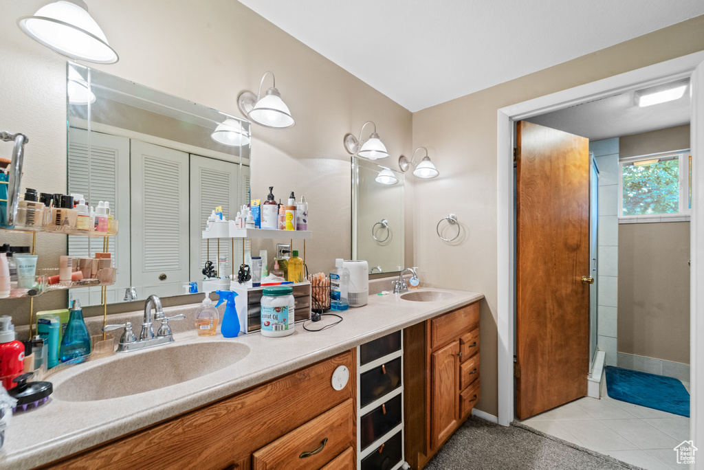 Full bath with double vanity, tile patterned floors, a closet, and a shower