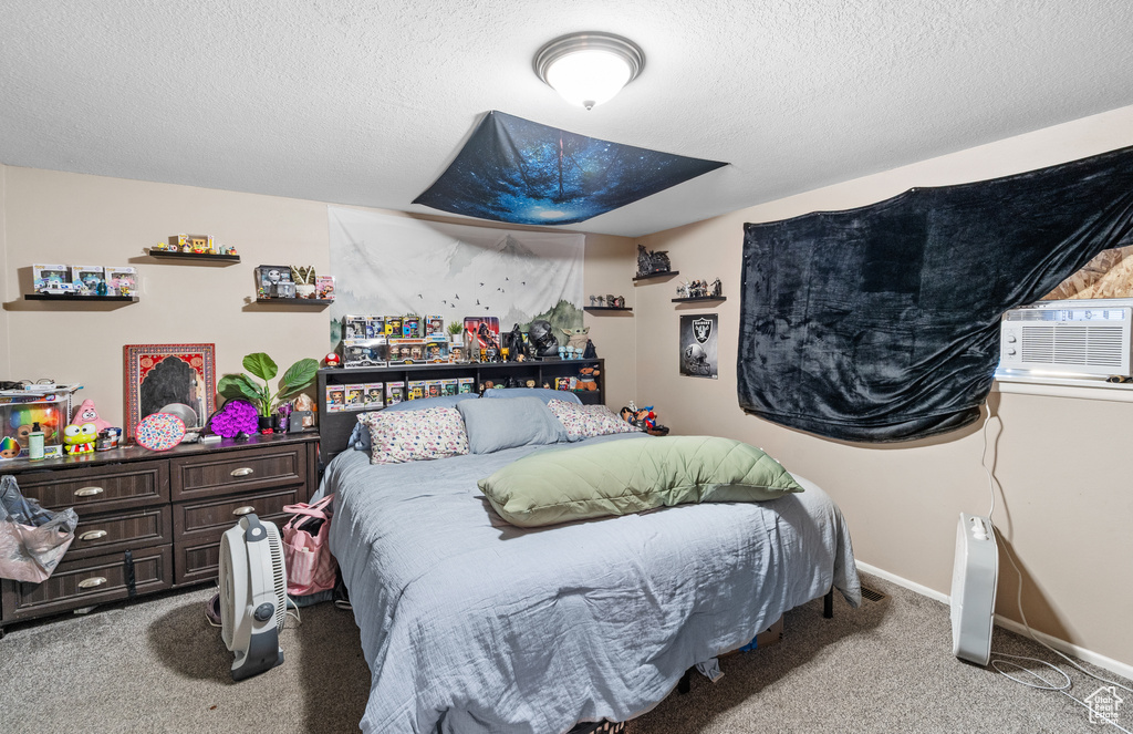Bedroom featuring carpet, cooling unit, and a textured ceiling