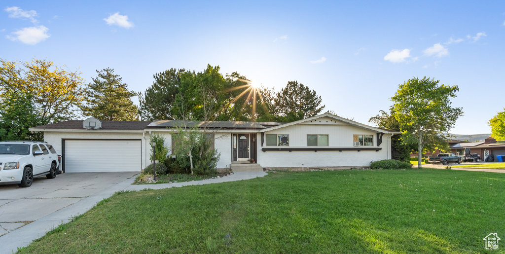 Single story home with a garage, a front yard, concrete driveway, brick siding, and solar panels