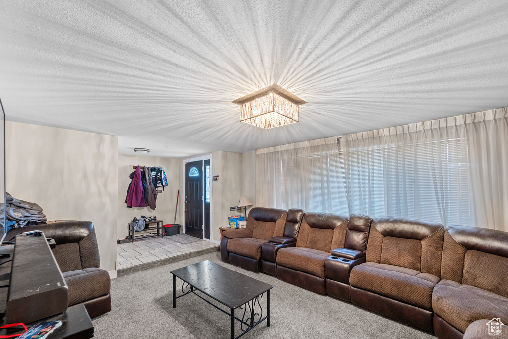 Carpeted living area featuring a chandelier and baseboards