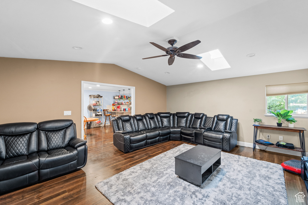 Living area with a skylight, lofted ceiling, wood finished floors, ceiling fan, and recessed lighting