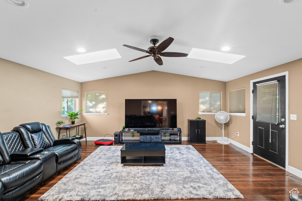 Living room with a skylight, a ceiling fan, dark wood-style floors, vaulted ceiling, and recessed lighting