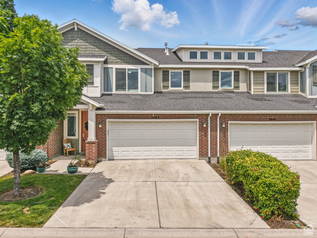 Multi unit property featuring a garage, concrete driveway, a shingled roof, and brick siding