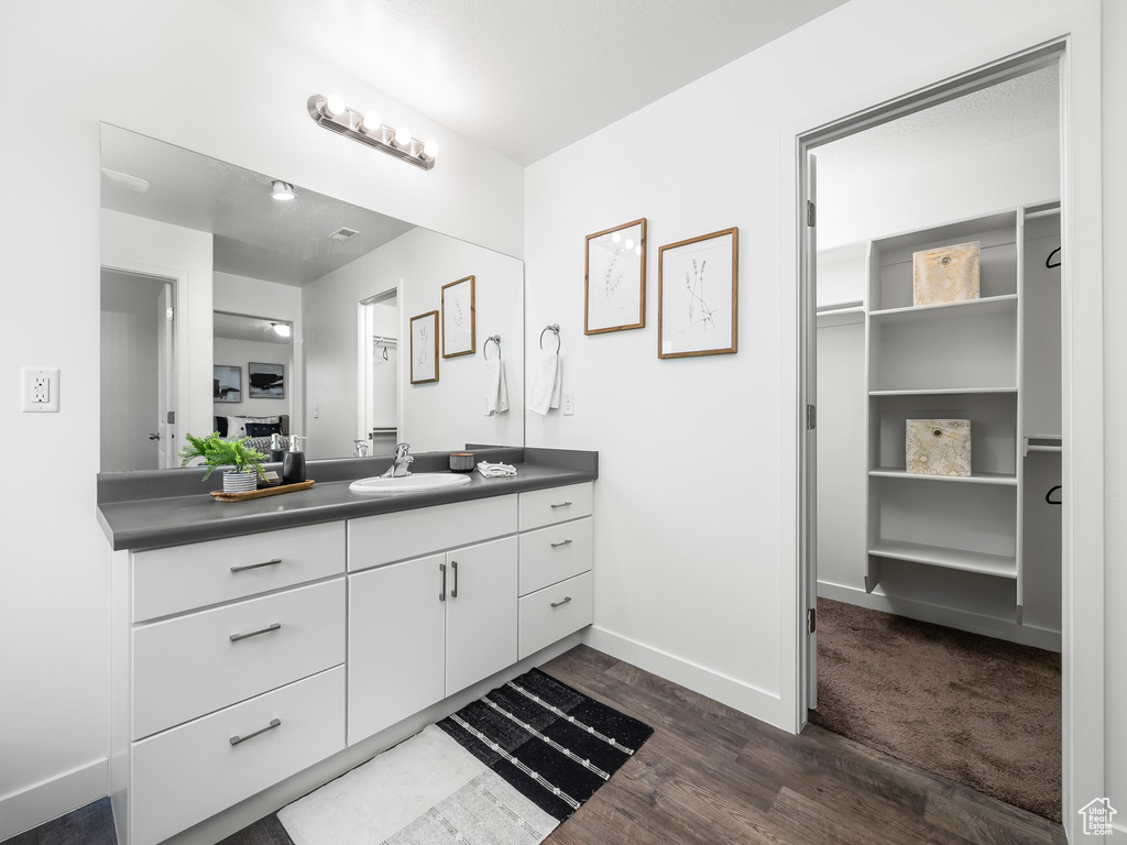Bathroom featuring vanity, wood finished floors, and a walk in closet