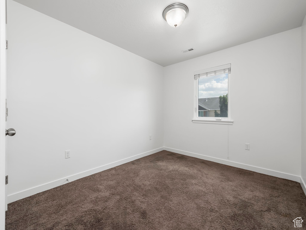 Unfurnished room with dark colored carpet and baseboards