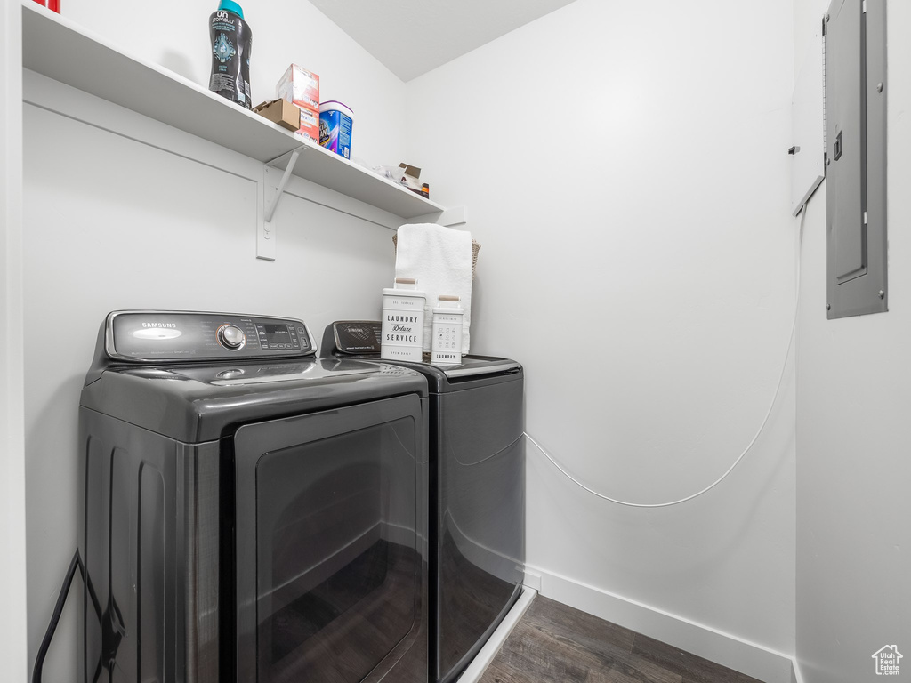 Washroom featuring washing machine and clothes dryer, electric panel, and dark wood finished floors