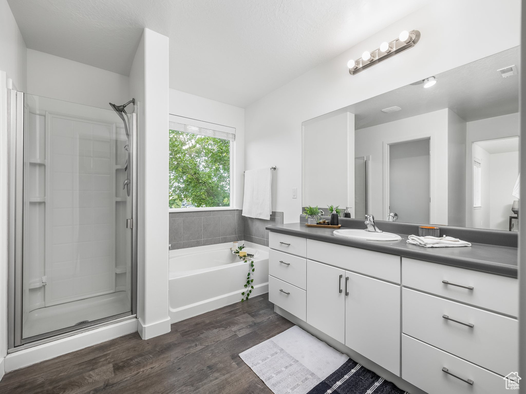 Full bath featuring vanity, a bath, wood finished floors, and a stall shower