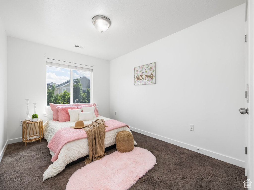 Bedroom with dark colored carpet and baseboards