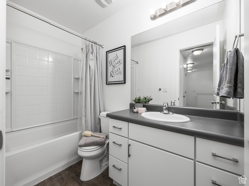 Full bathroom with vanity, shower / bath combo, and wood finished floors