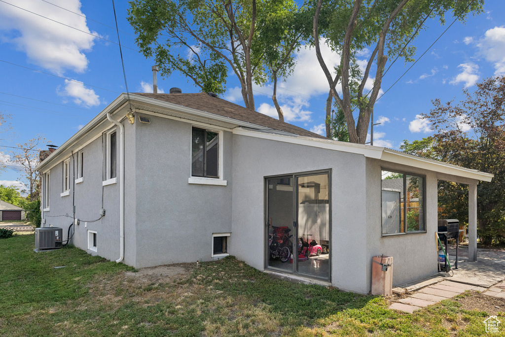 Back of house with stucco siding, a yard, and roof with shingles