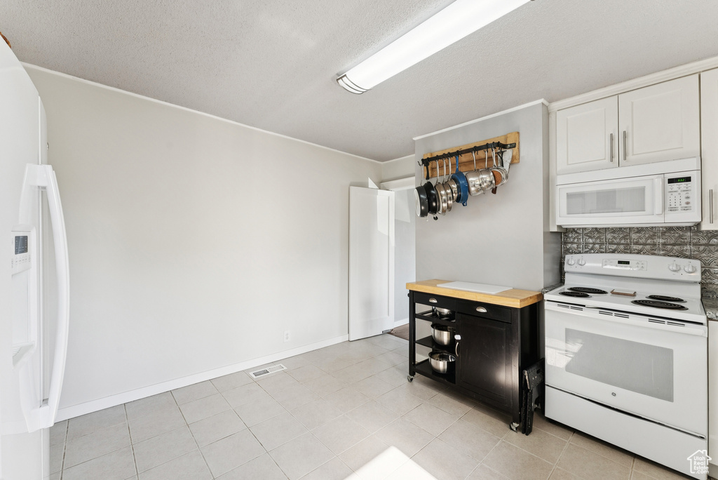Kitchen featuring white appliances, decorative backsplash, a textured ceiling, wood counters, and crown molding