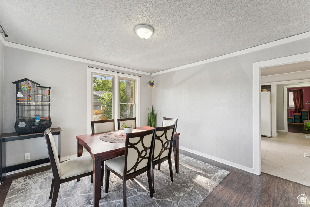 Dining room with a textured ceiling, wood finished floors, and ornamental molding