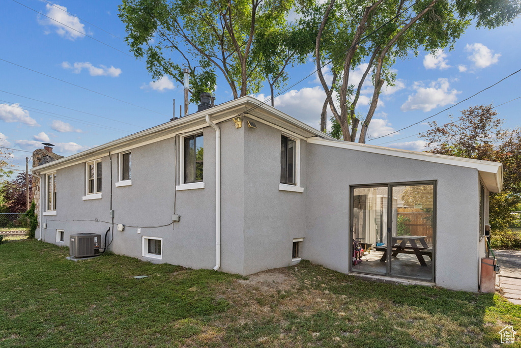 Rear view of house with stucco siding, a yard, a chimney, and a patio area