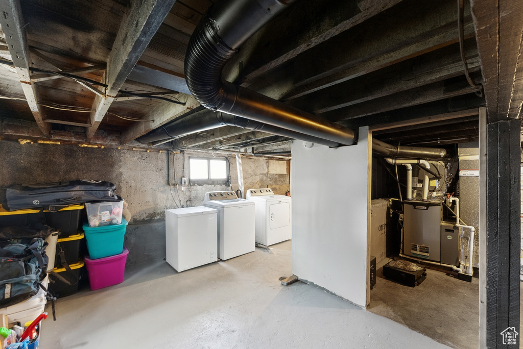 Basement featuring washer and dryer, refrigerator, and heating unit