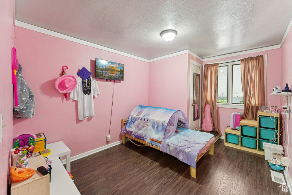 Bedroom featuring wood finished floors, a textured ceiling, and crown molding
