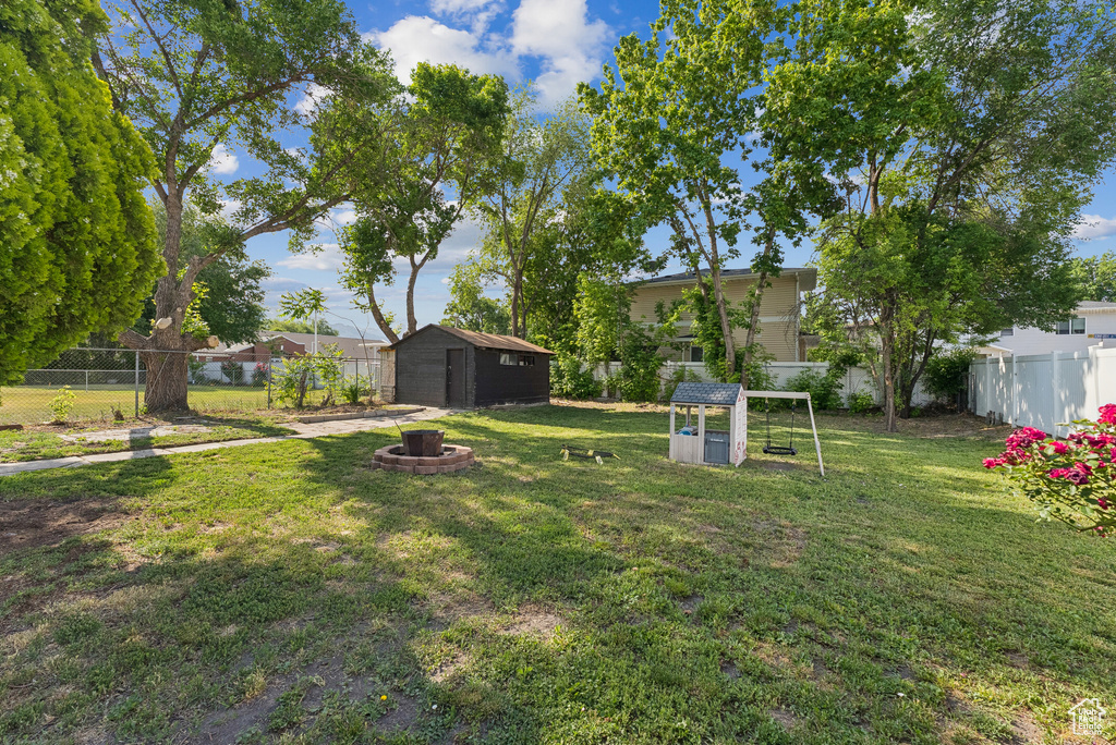 Fenced backyard with a storage unit and an outdoor fire pit