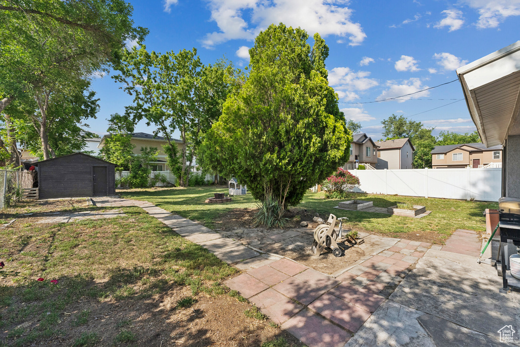 View of yard with a patio, an outdoor fire pit, a residential view, and a shed