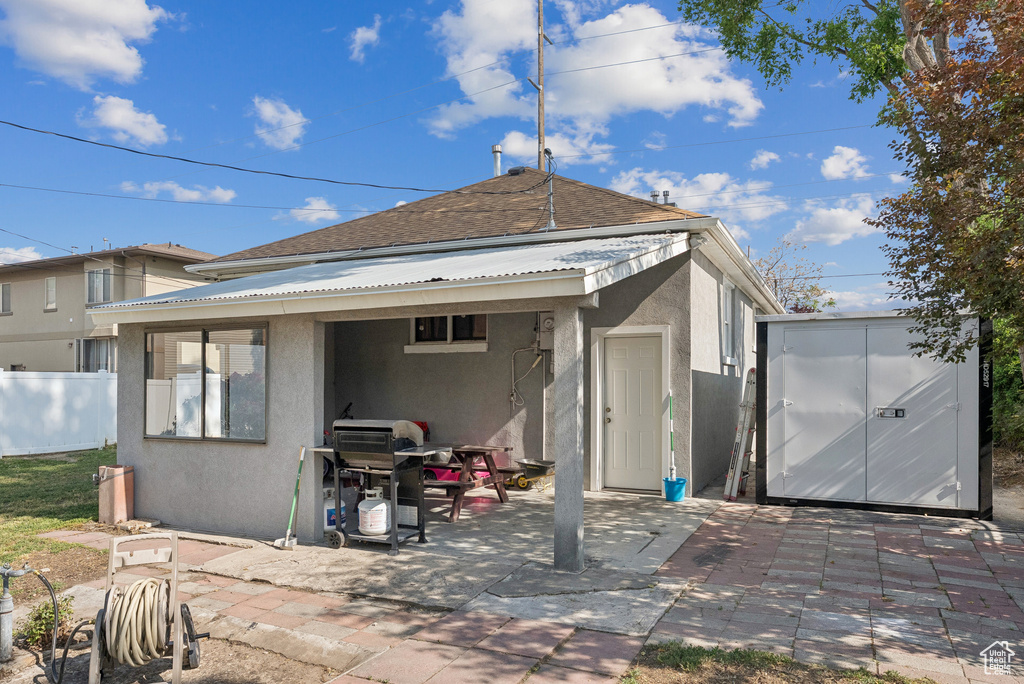 Back of property featuring stucco siding, a patio area, a shed, and a metal roof